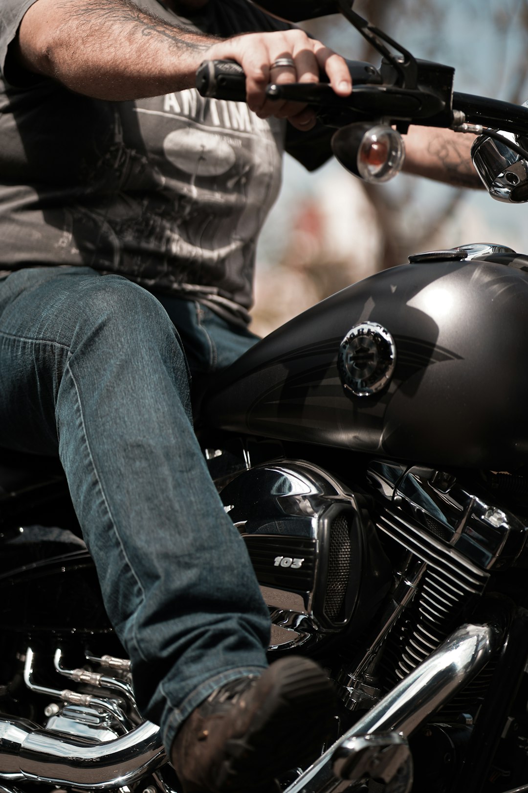 person in blue denim jeans sitting on black motorcycle