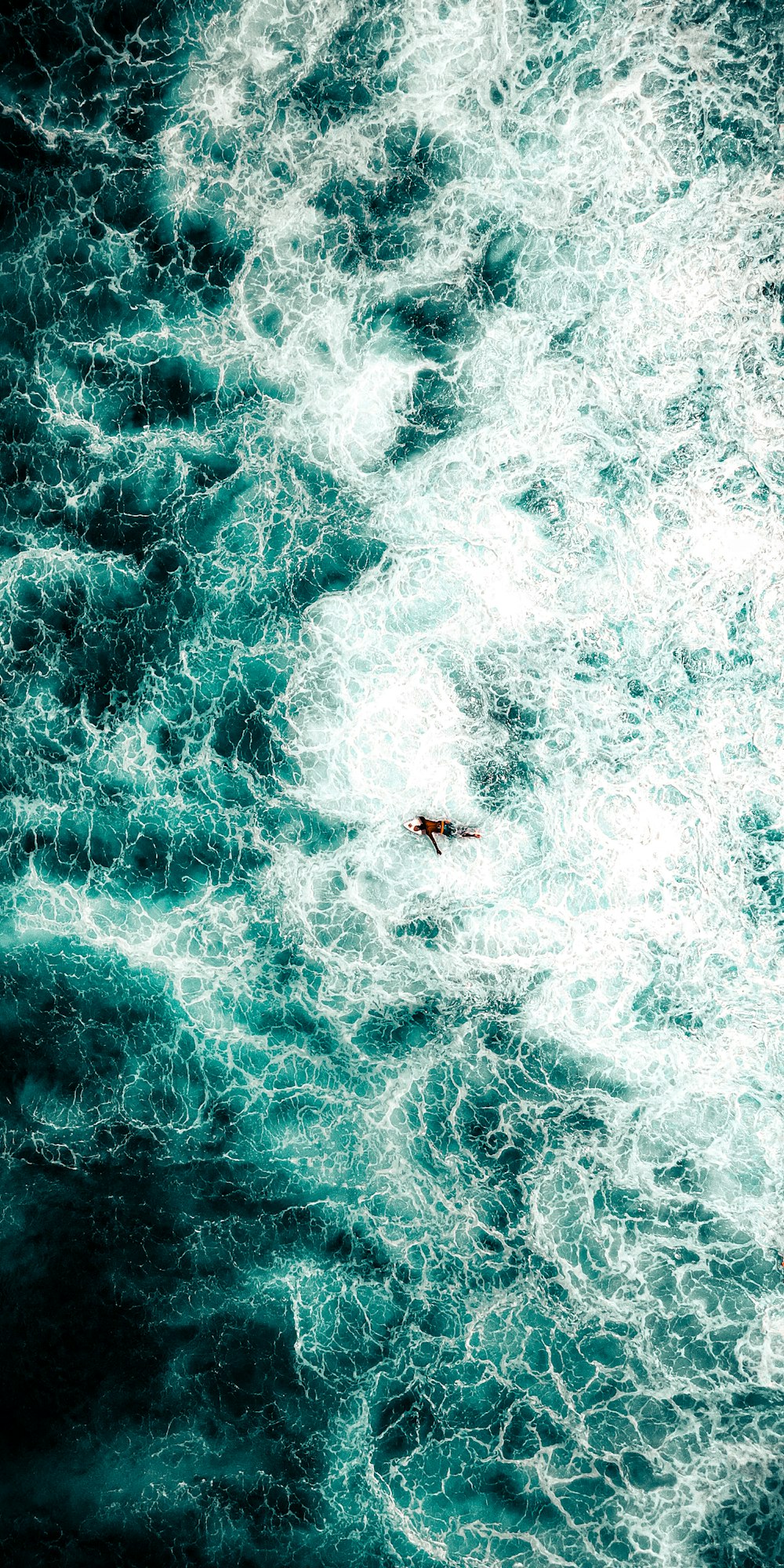 Persona surfeando en el agua azul del mar durante el día