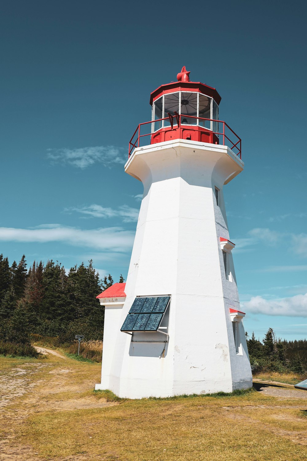 white and red concrete lighthouse under blue sky during daytime