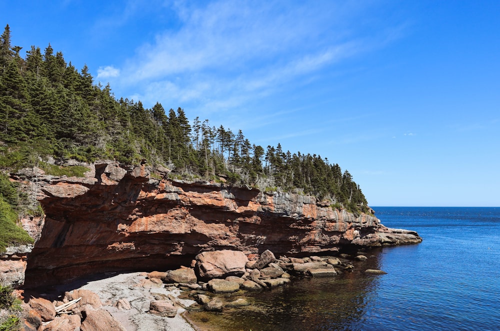 brown rocky mountain beside blue sea under blue sky during daytime