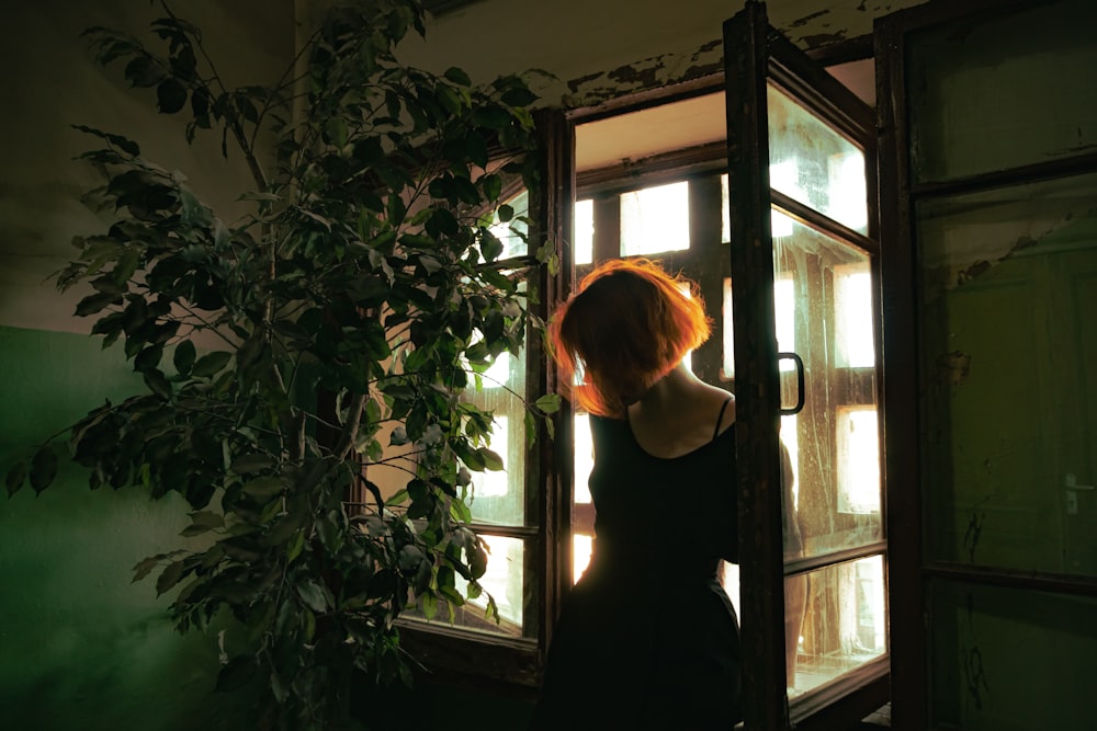 woman in black dress standing near window