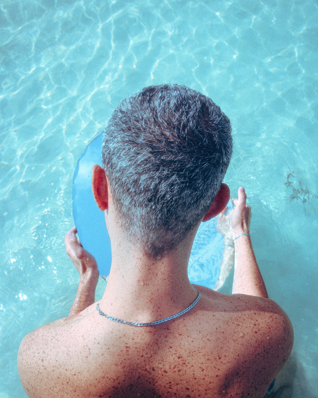 man in silver necklace in swimming pool