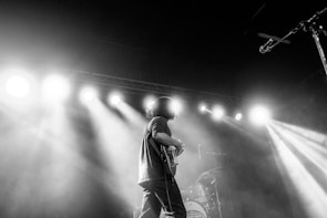 Hunter playing a sleek black solid-body guitar under moody stage lighting.