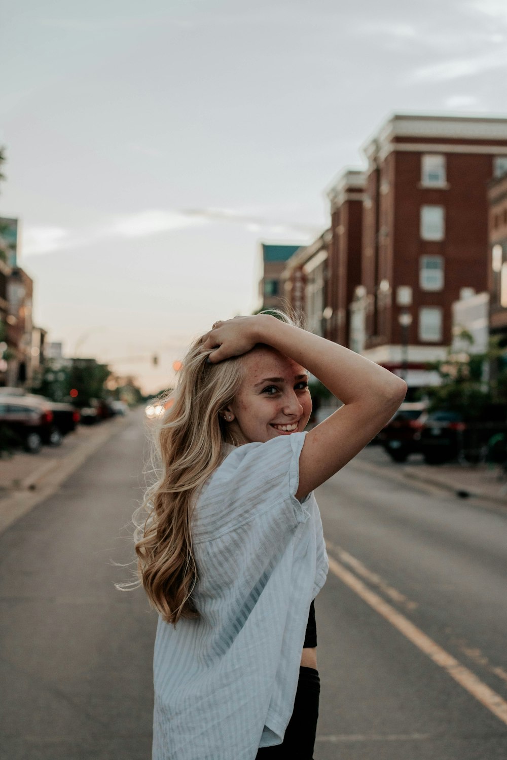 woman in gray shirt standing on road during daytime