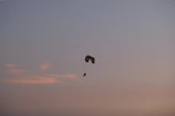 A paraglider drifting peacefully over the rugged Atlas Mountains at sunset.