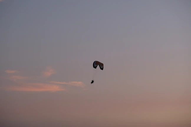 A paraglider drifting peacefully over the rugged Atlas Mountains at sunset.