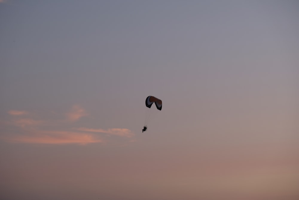 silhouette of person with parachute in mid air during sunset