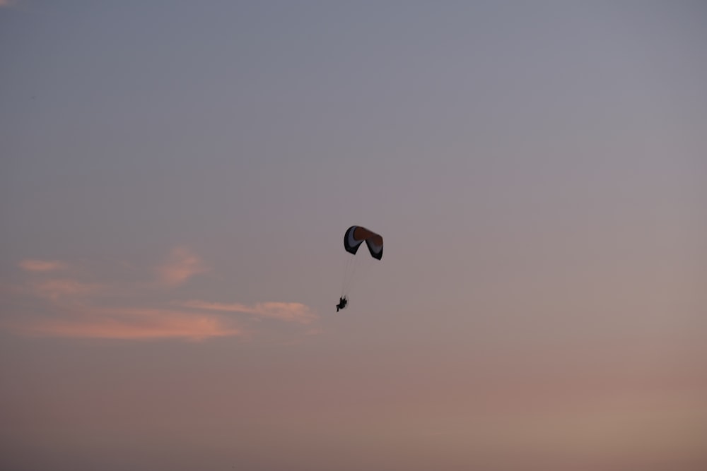 silhouette di persona con paracadute a mezz'aria durante il tramonto