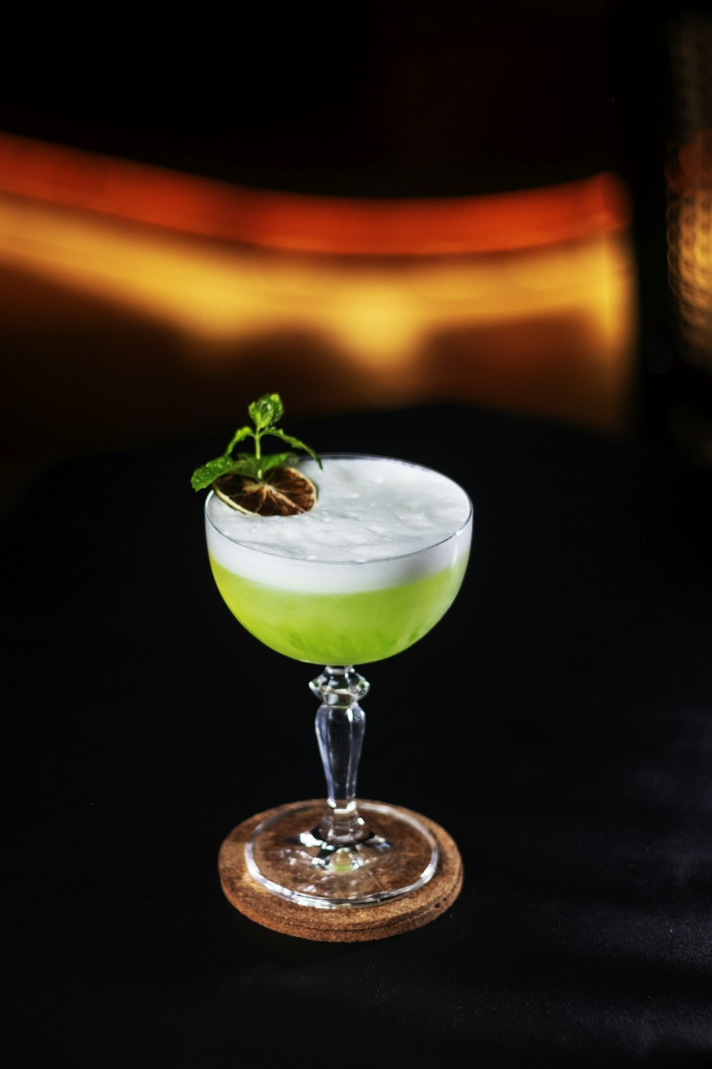 clear cocktail glass with green liquid on brown wooden table