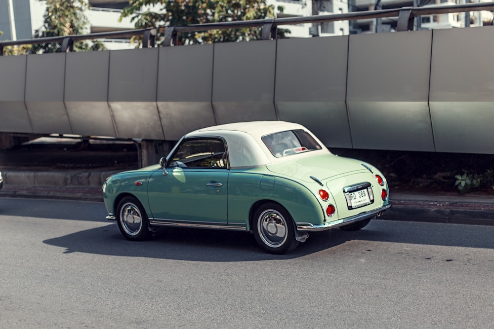 green car parked beside gray wall