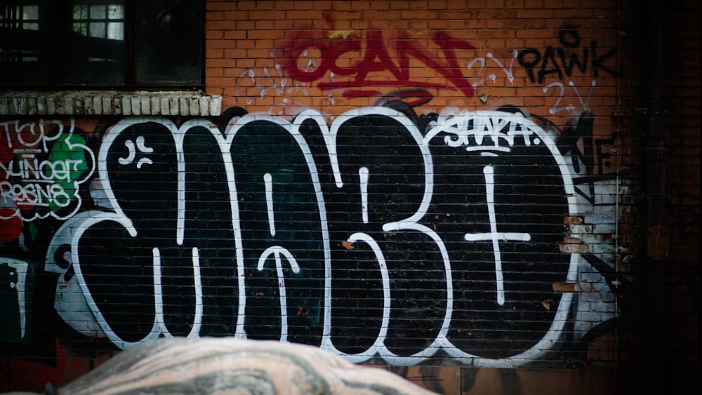 black and white graffiti on brown brick wall