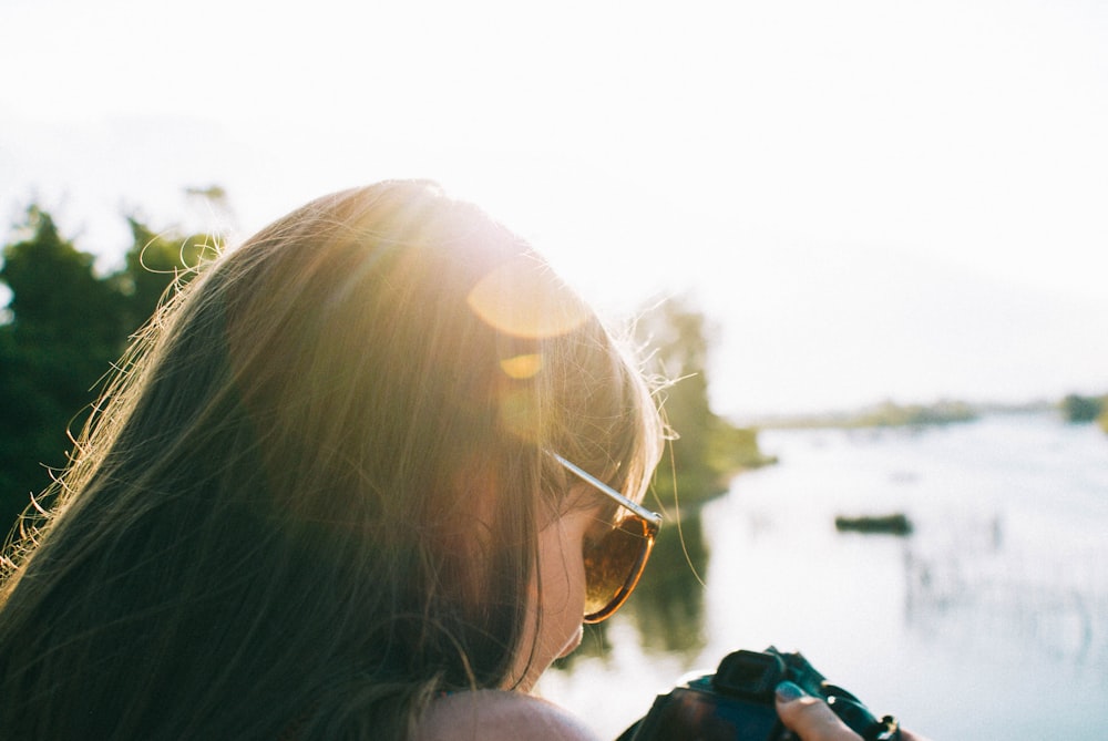 woman in black framed eyeglasses holding black dslr camera during daytime