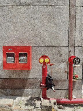 red fire extinguisher mounted on gray concrete wall