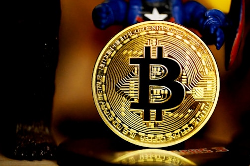 A golden Bitcoin coin with intricate circuit-like details is prominently displayed. It is held up by a figure wearing a blue costume.