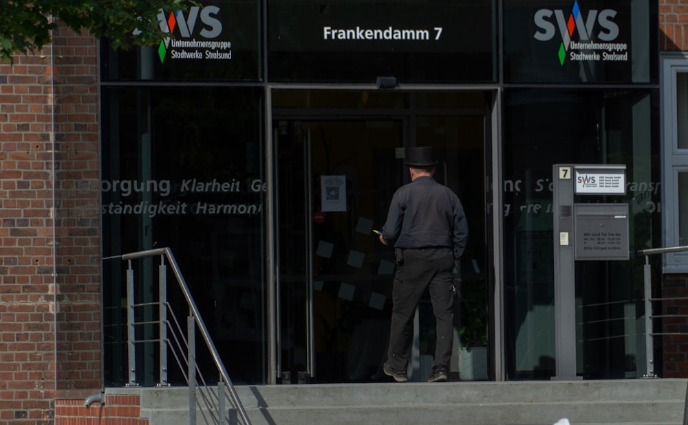 man in gray jacket and pants standing beside glass window