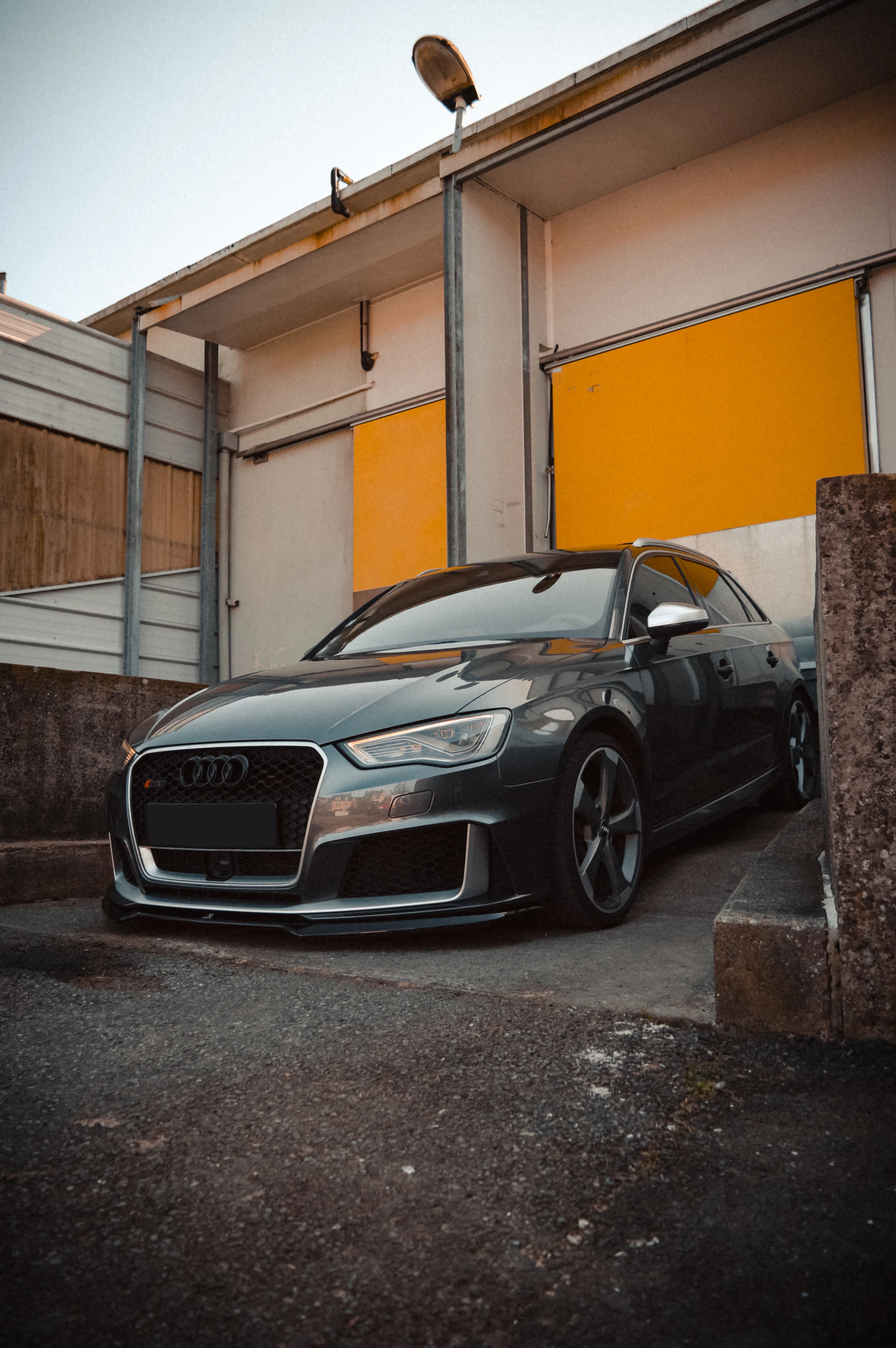 A sleek, modern car parked on a clean driveway, gleaming under soft yellow lighting that echoes the brand's color accents.