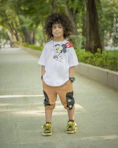 woman in white crew neck t-shirt and blue denim shorts standing on gray concrete road