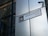 A street sign labeled 'HOUNDSDITCH EC3' is mounted on a modern building with reflective glass panels. The sign includes the City of London emblem. A security camera is positioned above the sign.