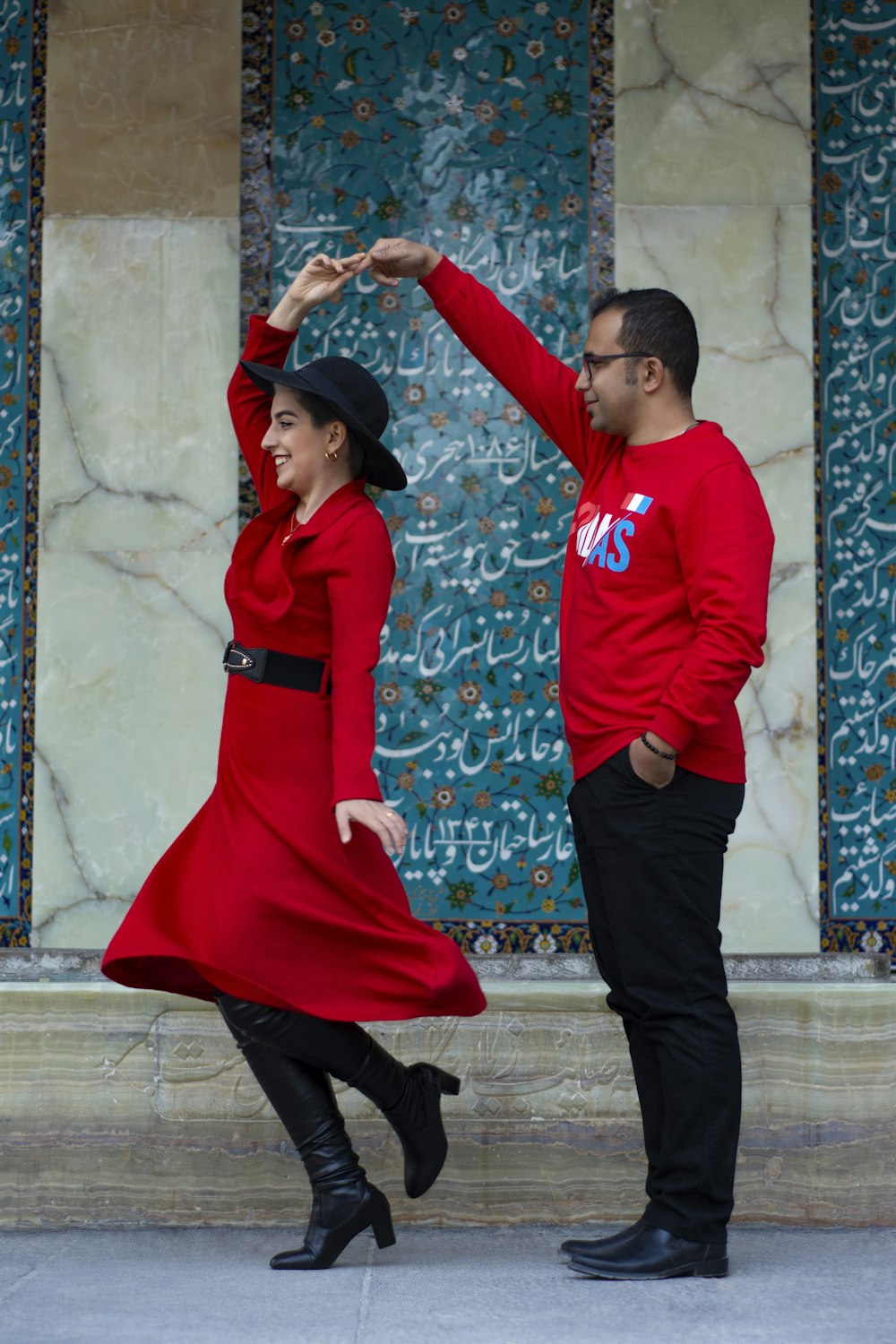 man in red long sleeve shirt and black pants standing beside woman in red long sleeve