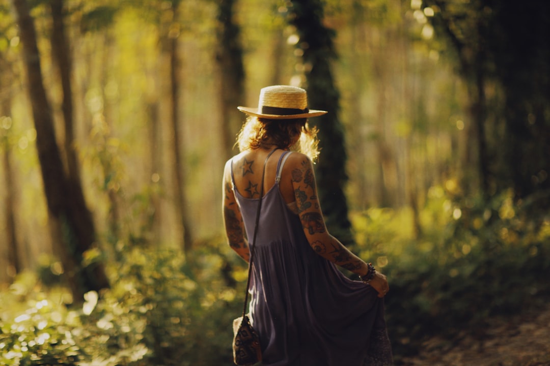 woman in brown cowboy hat and black dress standing in forest during daytime