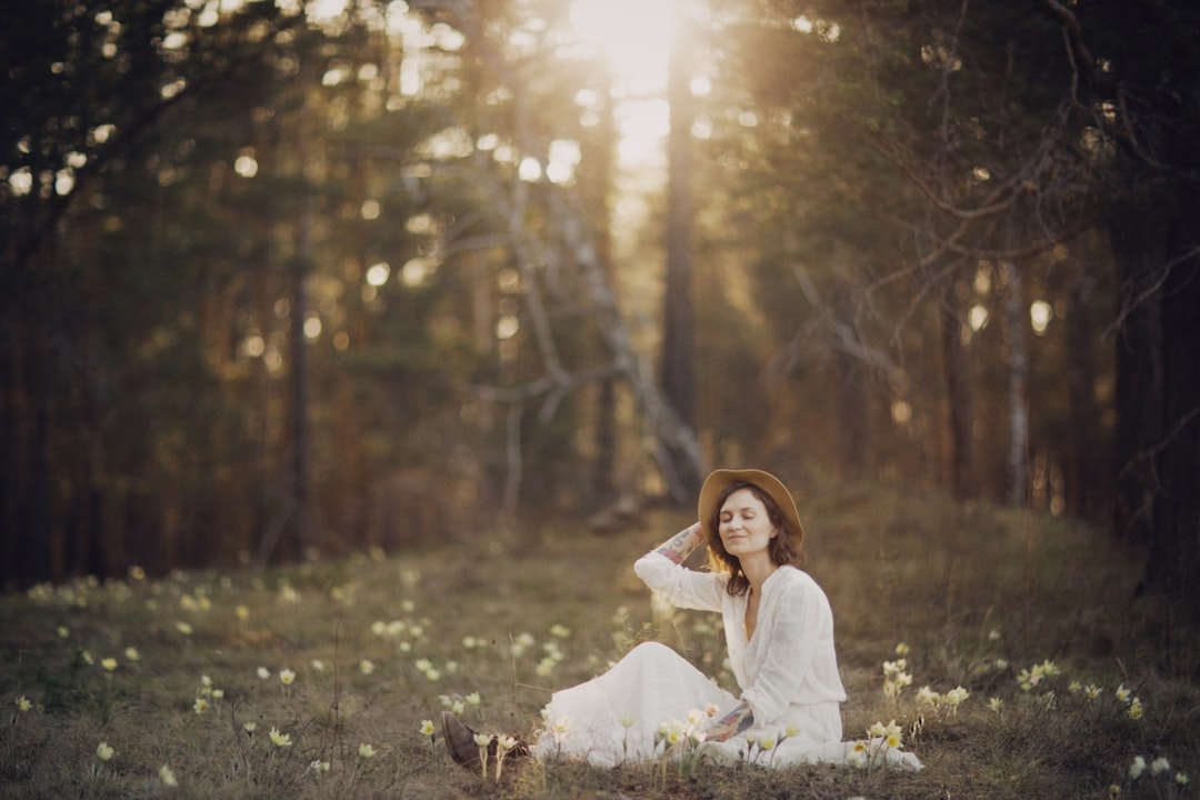 woman in white dress sitting on grass field during daytime