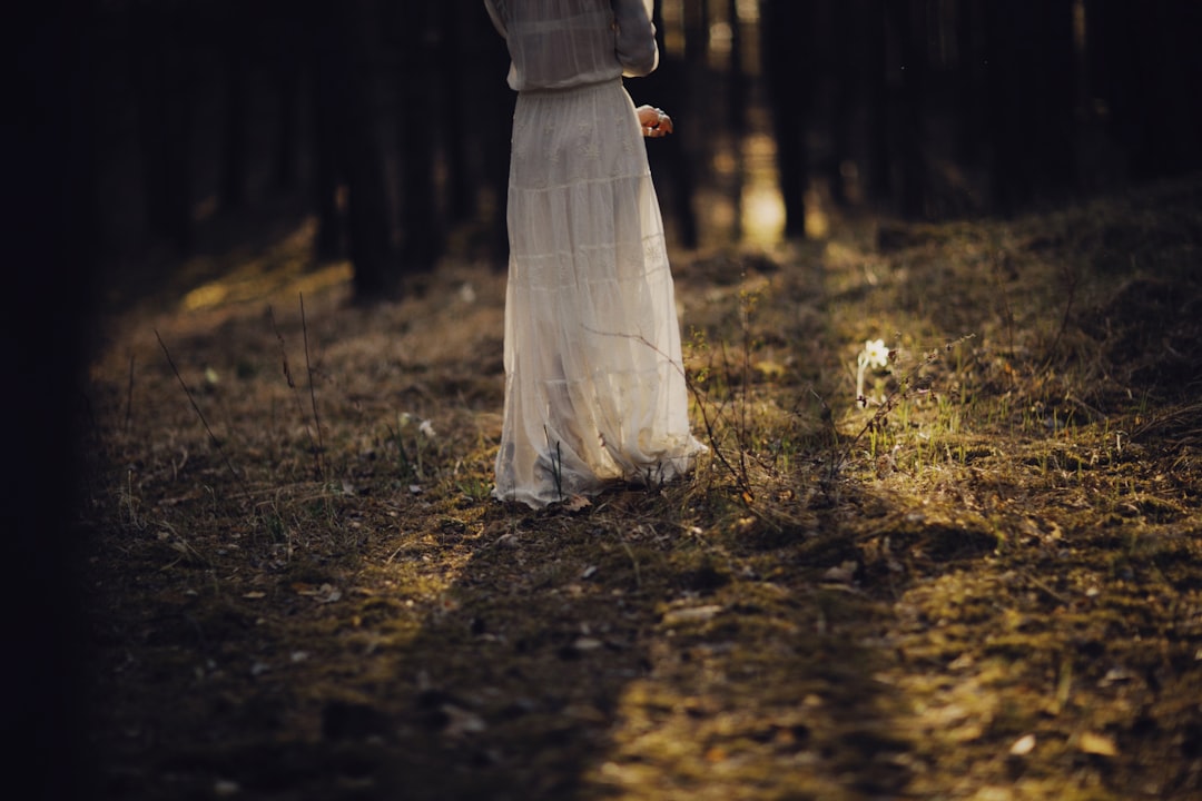 woman in white dress standing on brown dried leaves during daytime