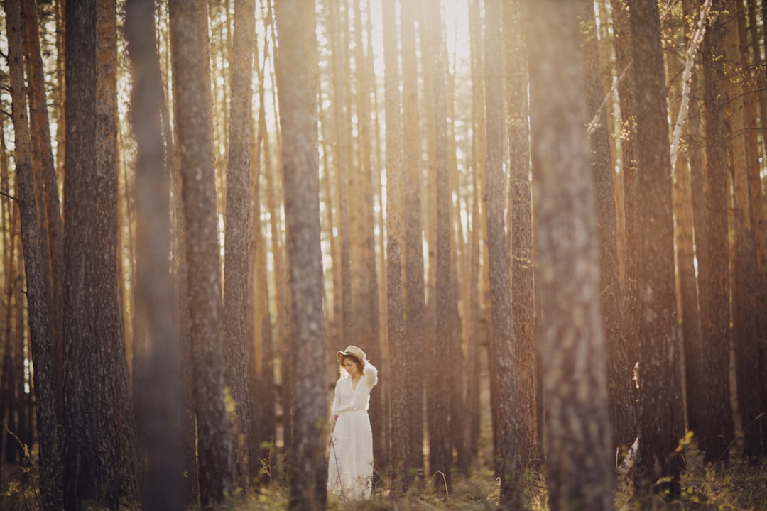 man and woman in white wedding dress standing on forest during daytime