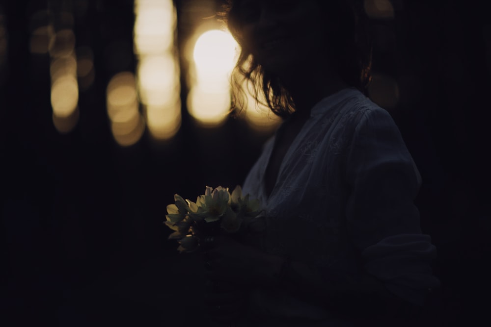 woman in white long sleeve shirt holding white flower