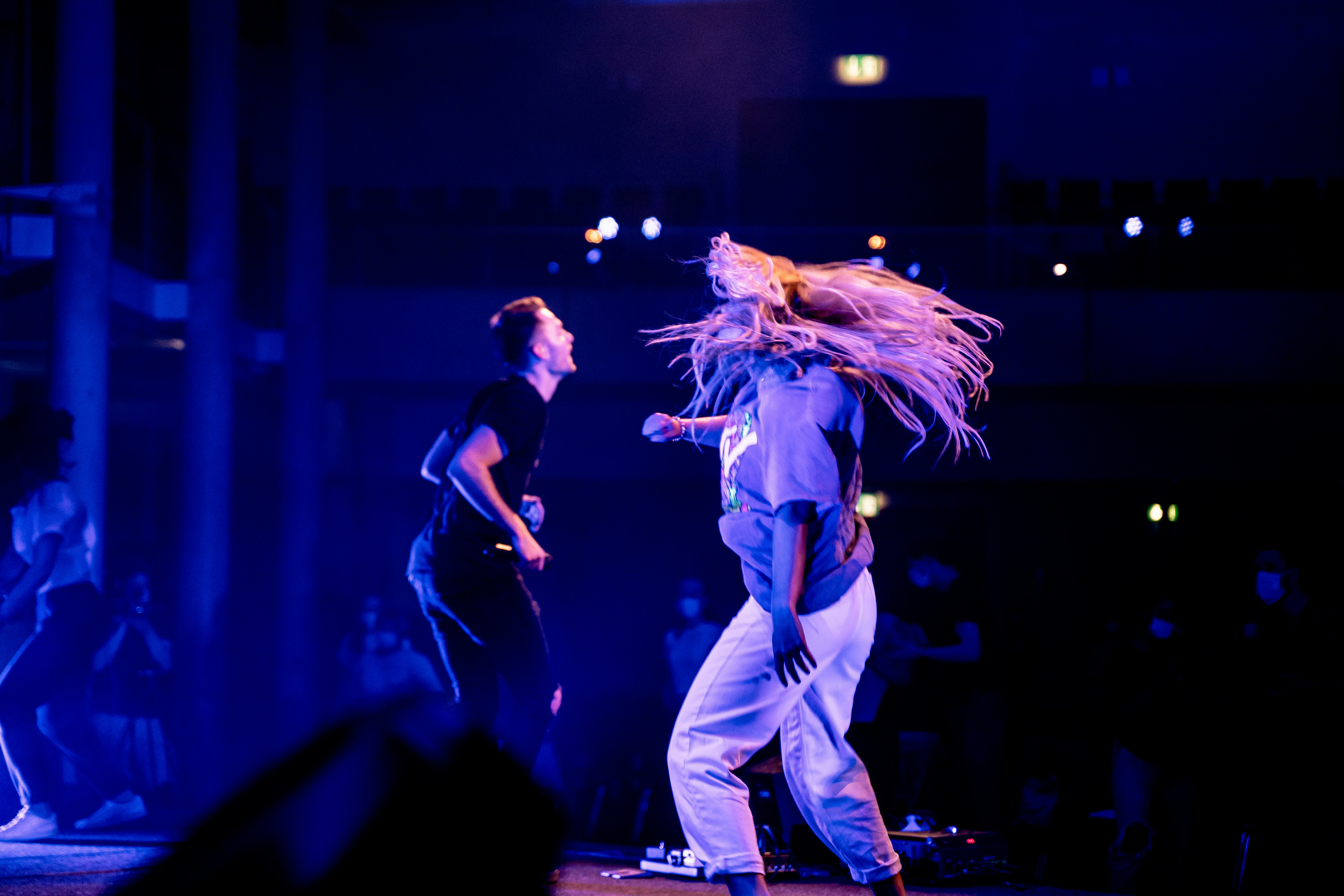 man in black tank top and white pants singing on stage