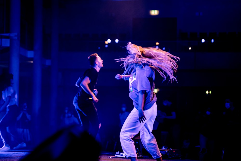 man in black tank top and white pants singing on stage