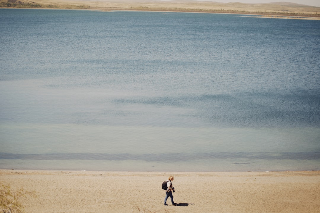 man in black shirt and black pants walking on brown sand beach during daytime