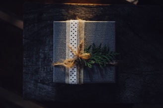 A beautifully wrapped gift box with a delicate ribbon, sitting on a rustic wooden table.