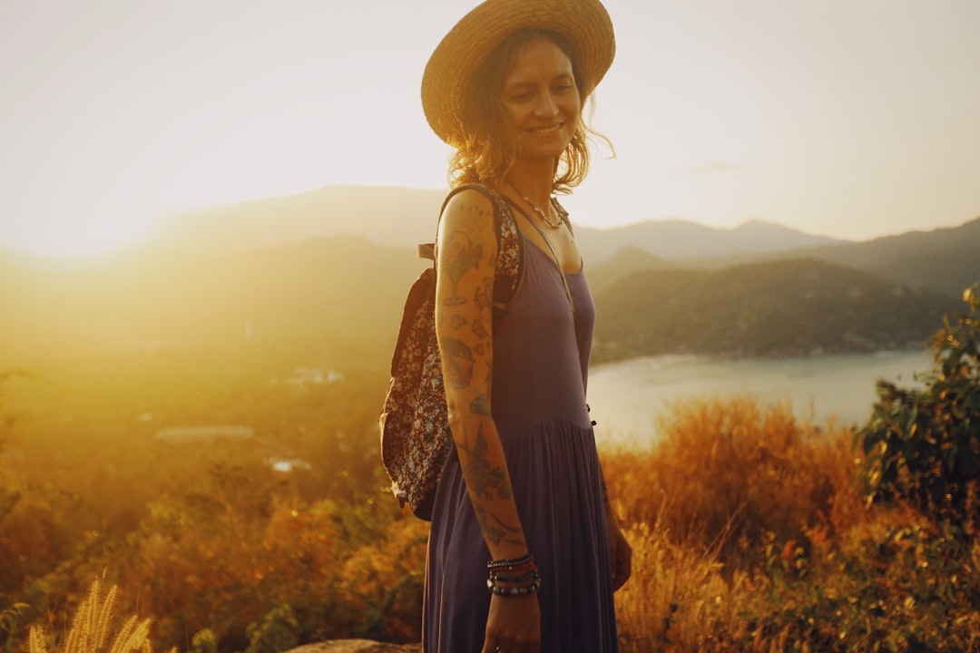 woman in black spaghetti strap dress wearing brown sun hat standing on brown grass field during