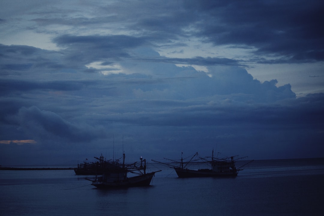 silhouette of boat on sea under cloudy sky during daytime