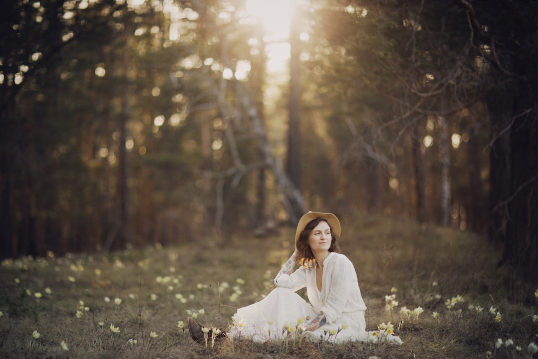 woman in white dress sitting on grass field during daytime