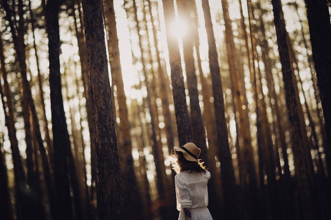 woman in white coat standing in forest during daytime