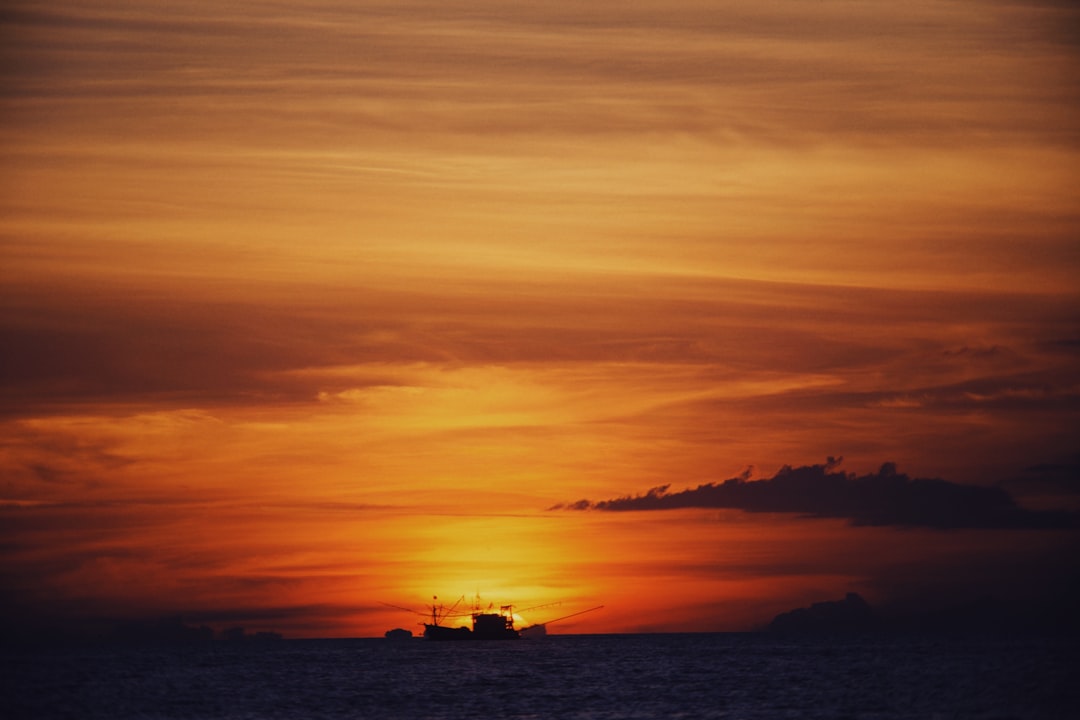 silhouette of boat on sea during sunset