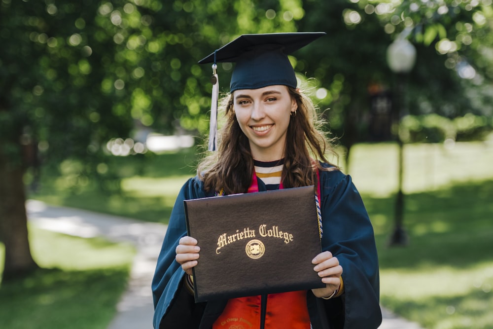 mulher no vestido acadêmico que usa o chapéu acadêmico