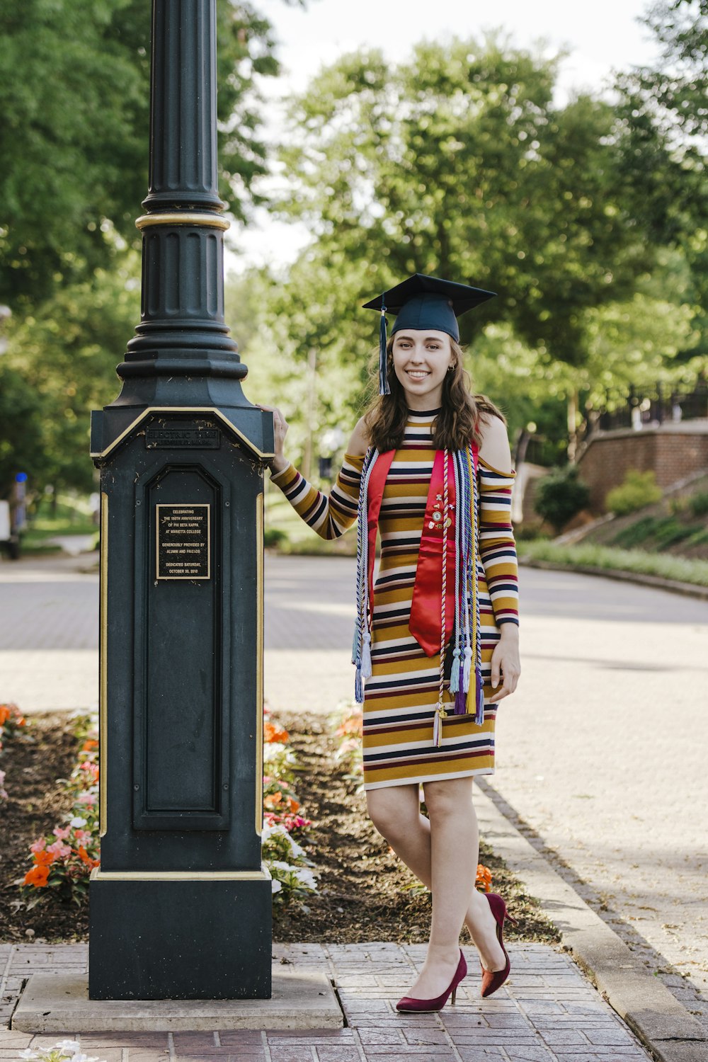 woman in black academic dress and black mortar board standing on sidewalk during daytime