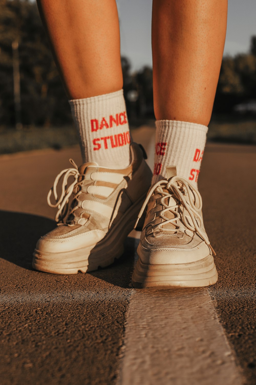 person wearing white and red socks and white adidas sneakers