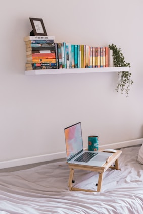 A cozy reading corner with shelves full of Islamic books and a laptop showing an online lecture.