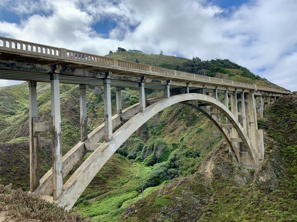 white bridge over green grass field under blue sky and white clouds during daytime