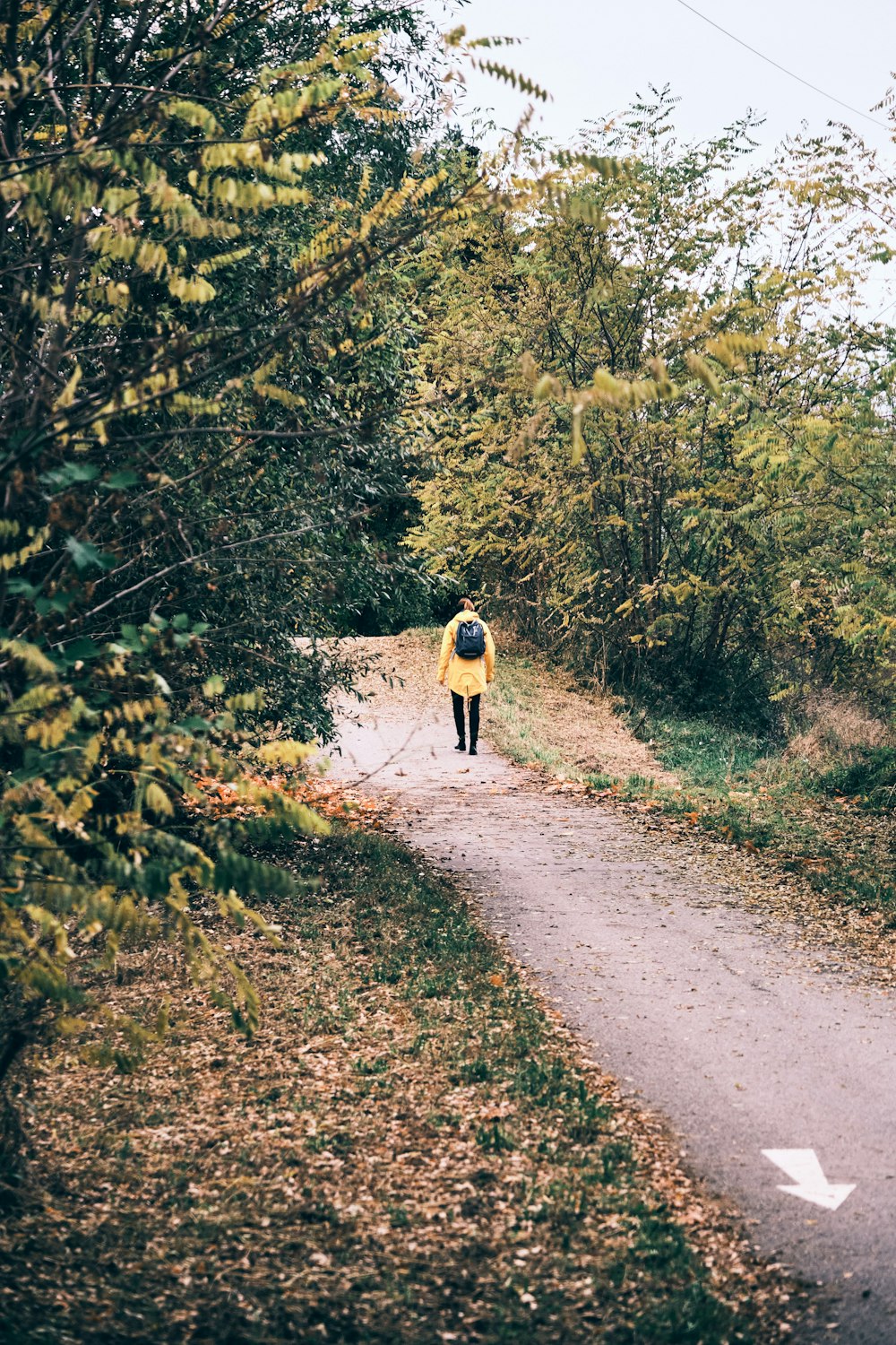 pessoa em jaqueta preta andando na estrada de terra durante o dia