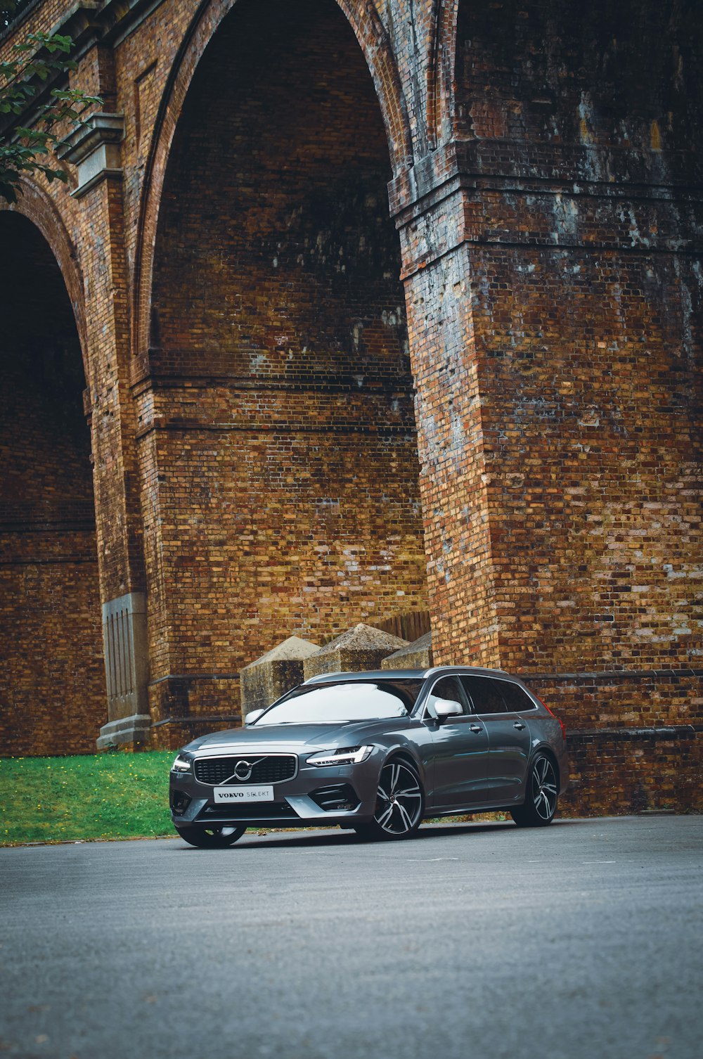 silver coupe parked beside brown brick wall