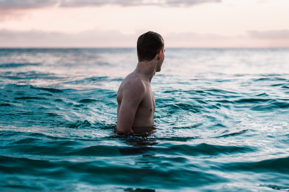 topless man in body of water during daytime
