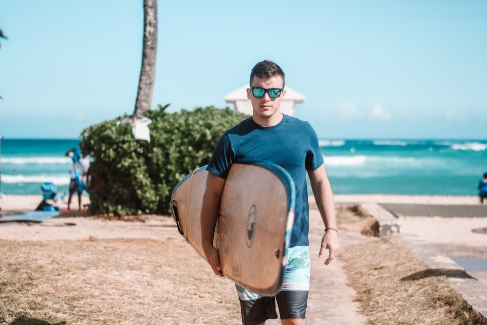 man in blue crew neck t-shirt and brown shorts standing on brown sand during daytime