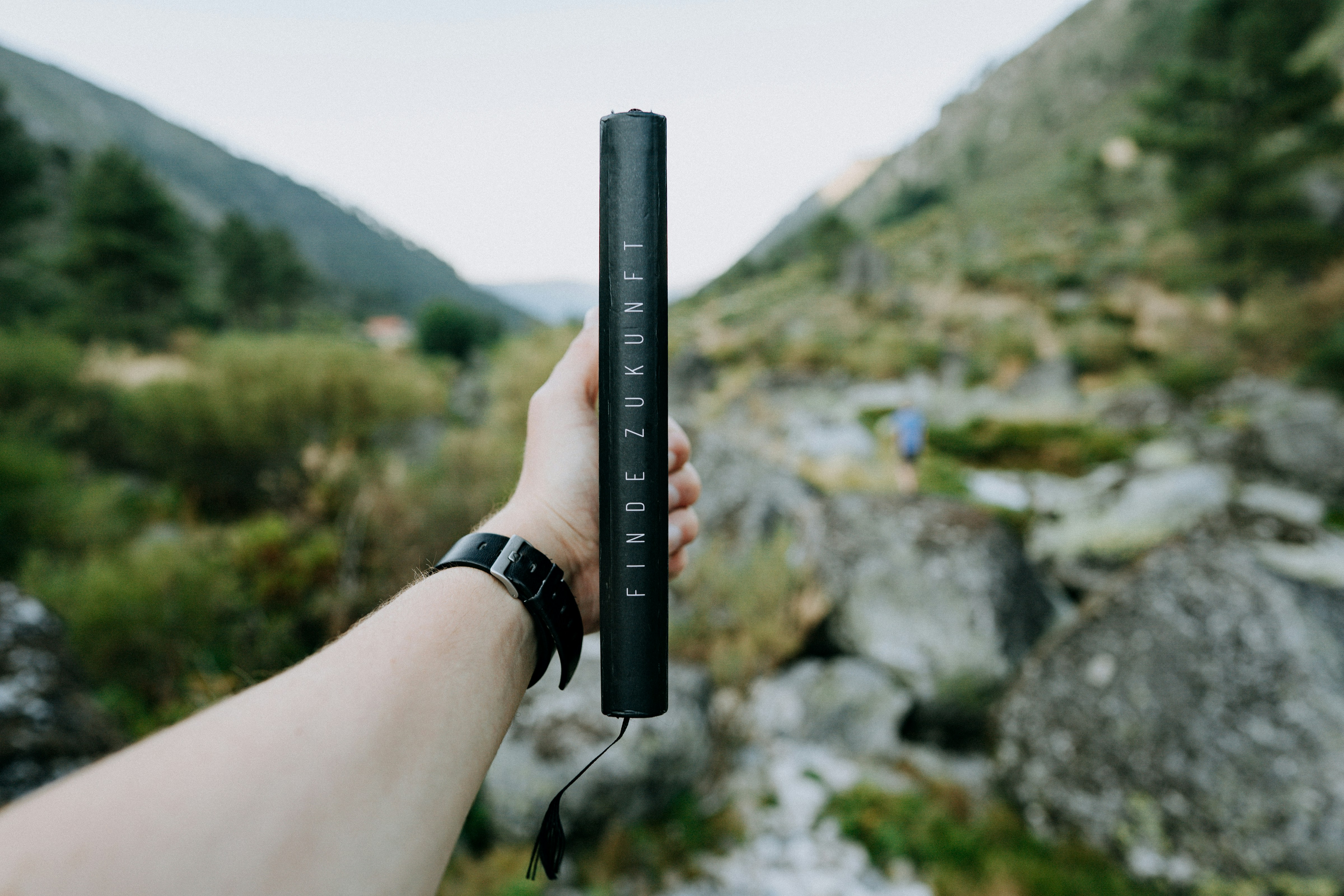 hand holding small cylindrical geocache container outdoors