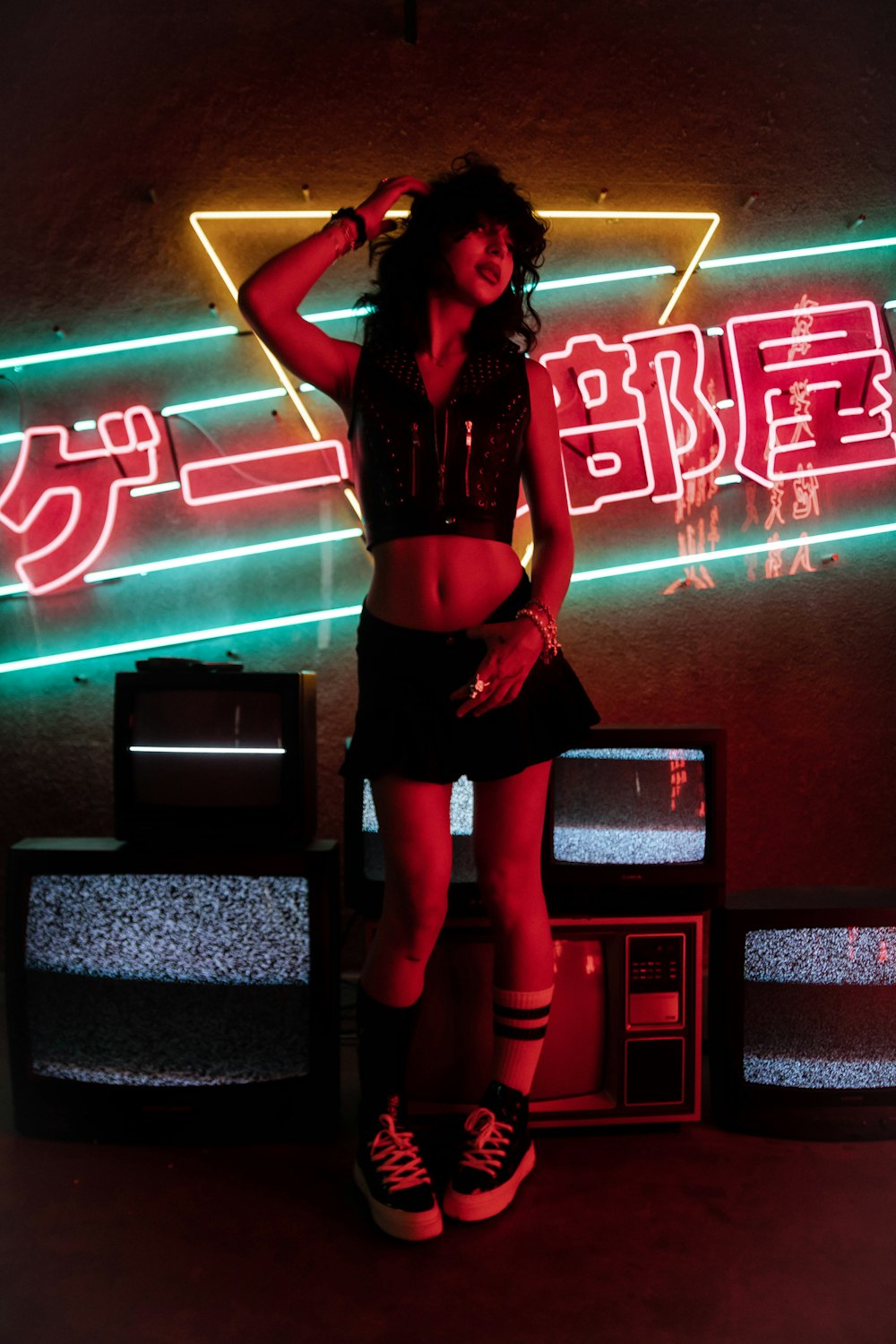woman in black tank top and red shorts standing on black and red neon light signage