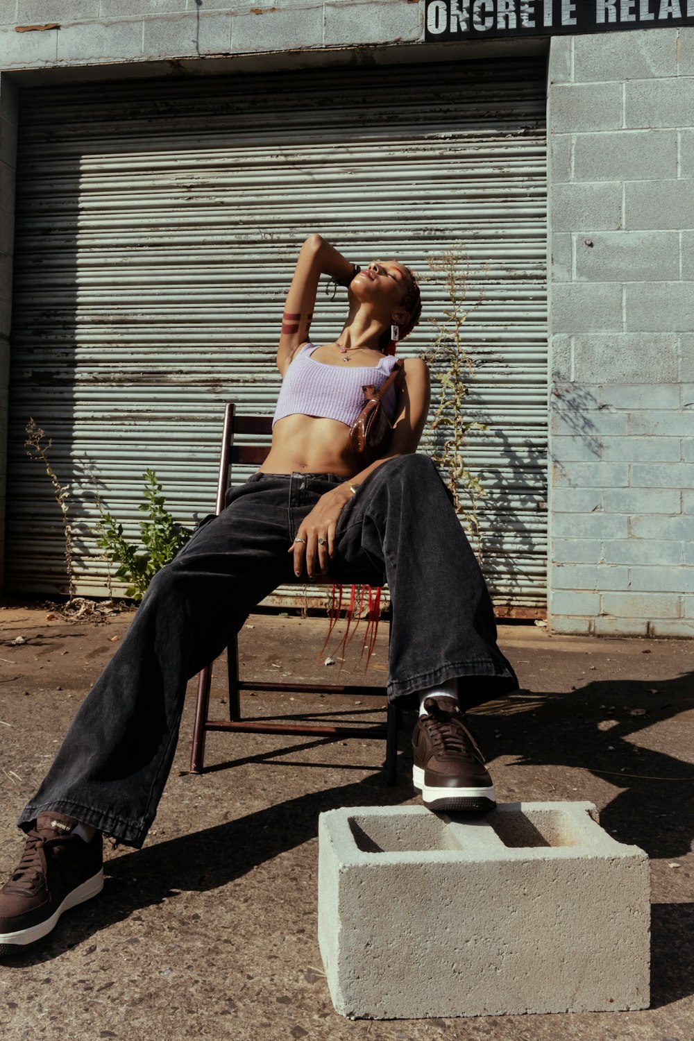 woman in white tank top and blue denim jeans sitting on black metal chair