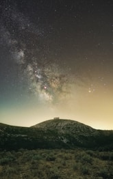 silhouette of house on hill under starry night